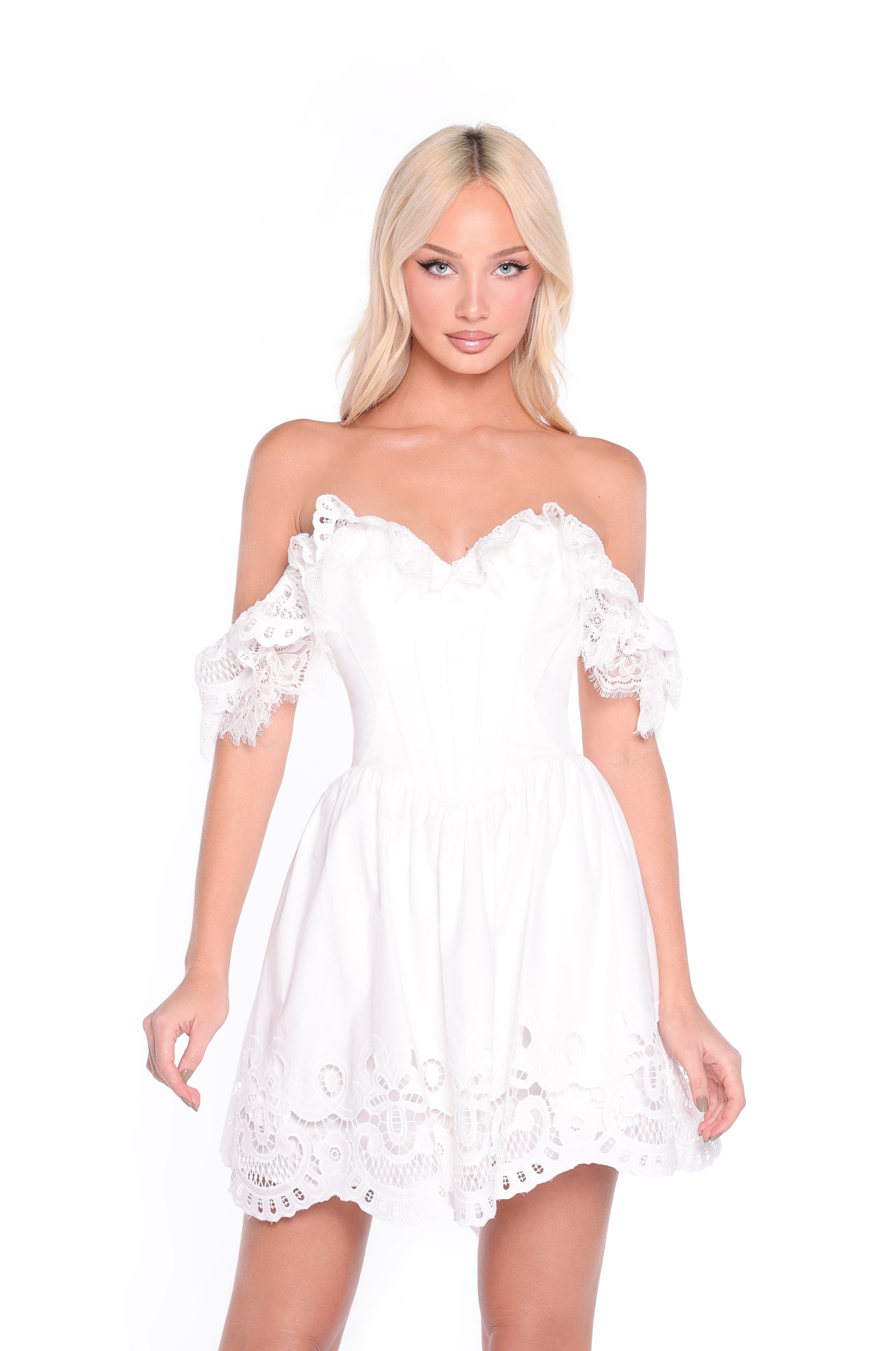 A woman wears the Cap-Sleeve Short Ivory Graduation Dress: Ari, featuring delicate lace details, while standing against a plain white background.